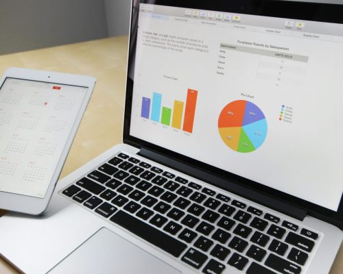Laptop displaying charts and graphs with tablet calendar for data analysis and planning.